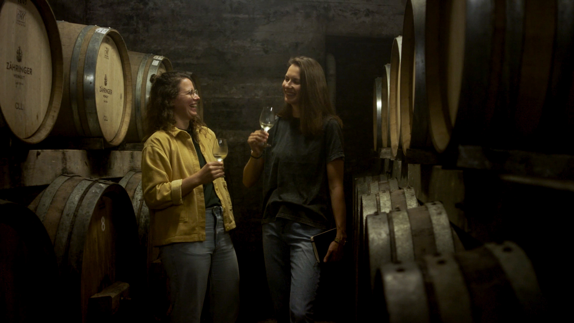 Leonie Berents und Silja Mende-Kapms im Weinerkeller, sie halten Weingläser in der Hand und probieren Wein