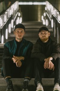 Die beiden Techno-DJs Luca Künstler und Lukas König, sitzen auf einer Treppe in einem U-Bahnhof. Als DJ-Duo machen sie unter dem Künstlernamen Krachwerk elektronische Musik und Techno.