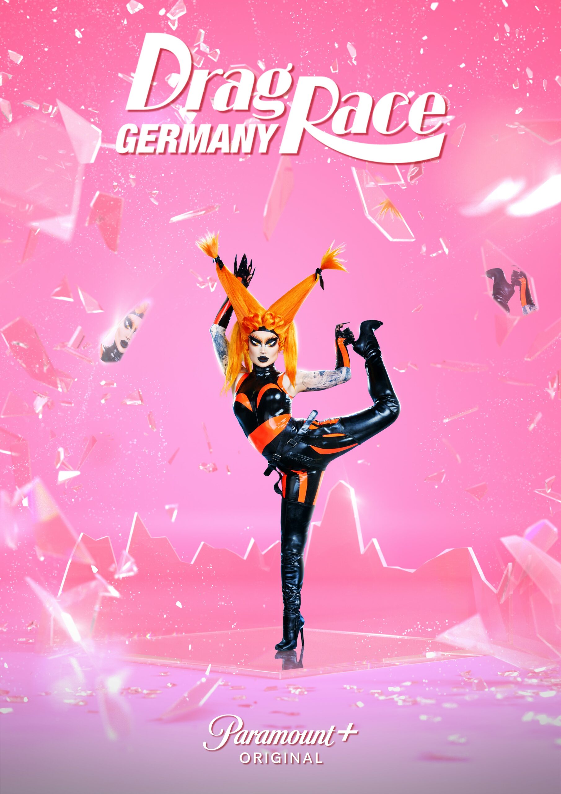 Pandora Nox Gewinnerin von Drag Race Germany steht in ihrem Promo Look zu Drag Race Germany mit erhobenem Bein auf einer Spiegelfläche. Sie trägt eine Kombination aus orange und schwarz.