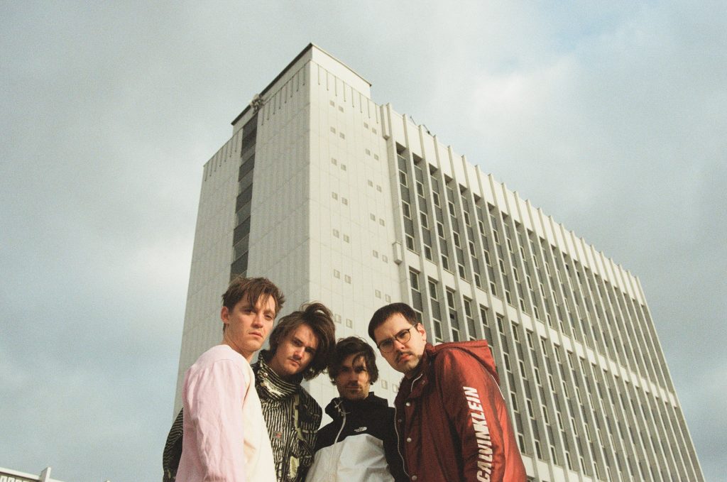 Die Band Pudeldame aus Lübeck besteht aus Jonas Nay, David Grabowski, Jon Klein und Nico Bauckholt. Die vier stehen Arm in Arm vor einem Hochhaus. Das Foto ist von Jan Philipp Schünke