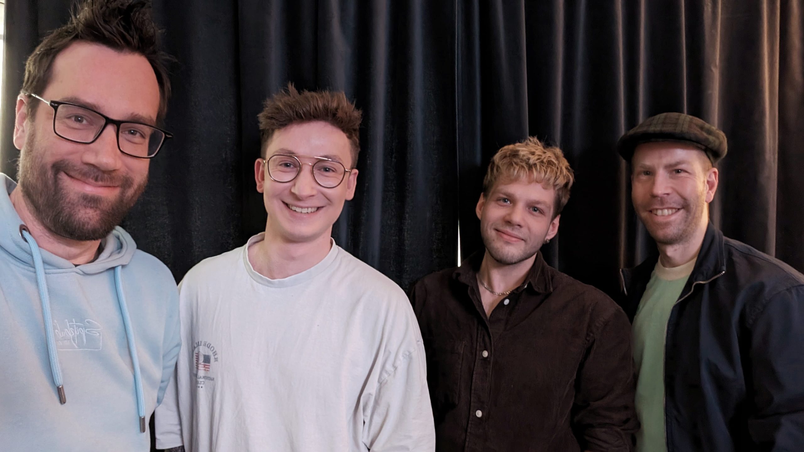 Simon Lösch und Waldemar Rusch sind die Gründer von Sparkful. In ihrem Unternehmen geht es um Diversity. Links neben den beiden steht Host Sebastian. Rechts steht Host Toni. Alle vier lächeln in die Kamera.