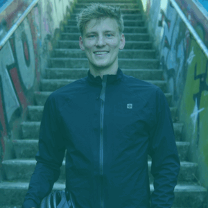 Fabian Abel aus Köln erzählt im achten Interview von seiner schwersten Etappe: Der Radtour durch die Sahara. Auf dem Foto trägt Fabian eine blaue Windjacke und hat den Fahrradhelm in seiner rechten Hand. Die Linke hat steckt in seiner Hosentasche. Fabian schaut nach rechts und lächelt. Das Foto unterliegt dem Copyright von Fabian Abel