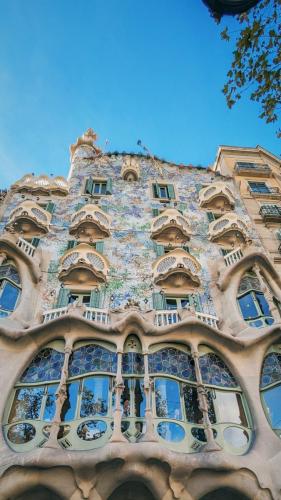 Das Bild zeigt die Fassade der berühmten von Antoni Gaudi entworfenen Casa Batllo. Das Bild wurde bei Tag aufgenommen und die Fasse ist mit reichen Verzierhung und den berühmten Balkonen versehen, die Totenköpfe symbolisieren sollen.